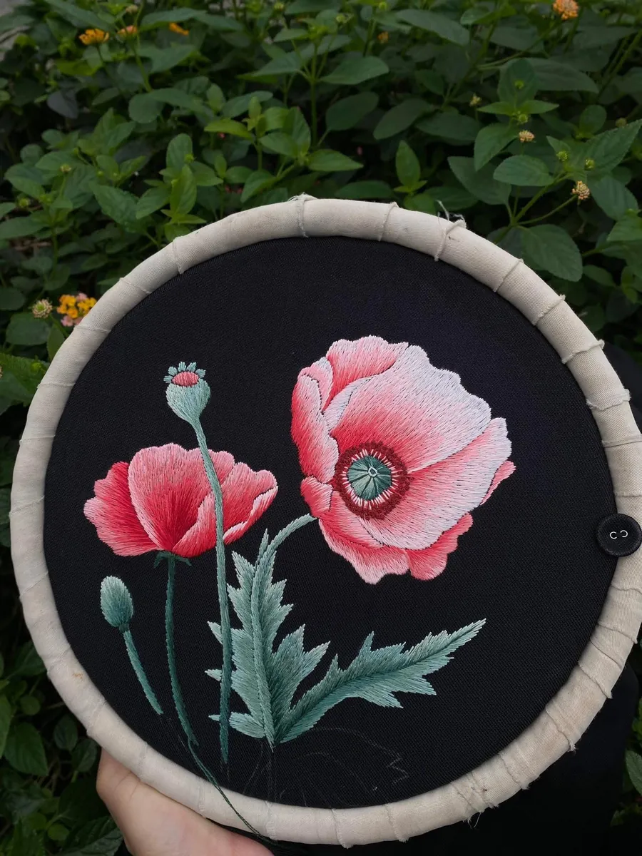 Pink flowers embroidered by hand on a black fabric