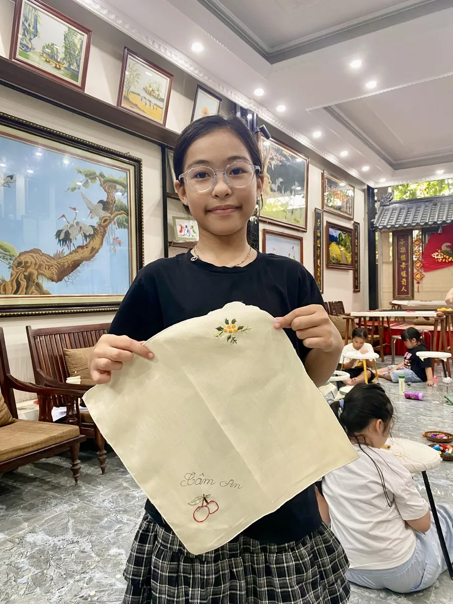 A participant holding up an embroidered cloth at Vị & Thêu