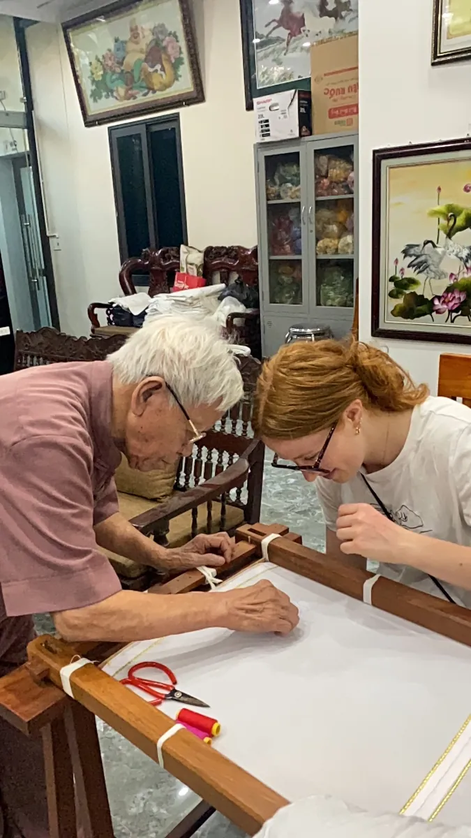 Two participants concentrating on embroidery at a table at Vị & Thêu